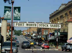 Fort Worth Stock Yards sign above Exchange Avenue. The White Elephant Saloon is to the right, H3 Ranch and the Buffalo Butt Saloon to the left.