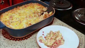 A serving of baked King Ranch Chicken Casserole is being scooped from a blue dish onto a white plate