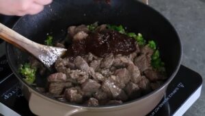 Seared beef is returned to the pot with sautéed aromatics and chili paste to build the base for Texas chili