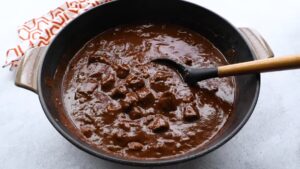 Thick, rich Texas chili simmers in a pot, ready to serve with tender beef chunks in a dark, flavorful sauce