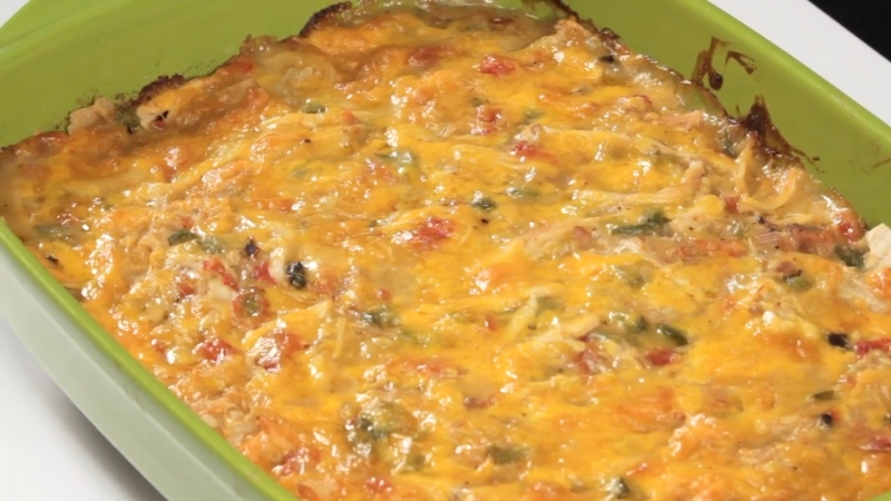 King Ranch Chicken Casserole baked in a green dish, with melted cheese on top and visible peppers and tomatoes