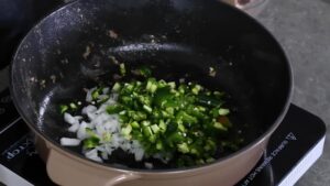 Chopped onions and green chilies are being sautéed in a pot to build the flavor base for Texas chili